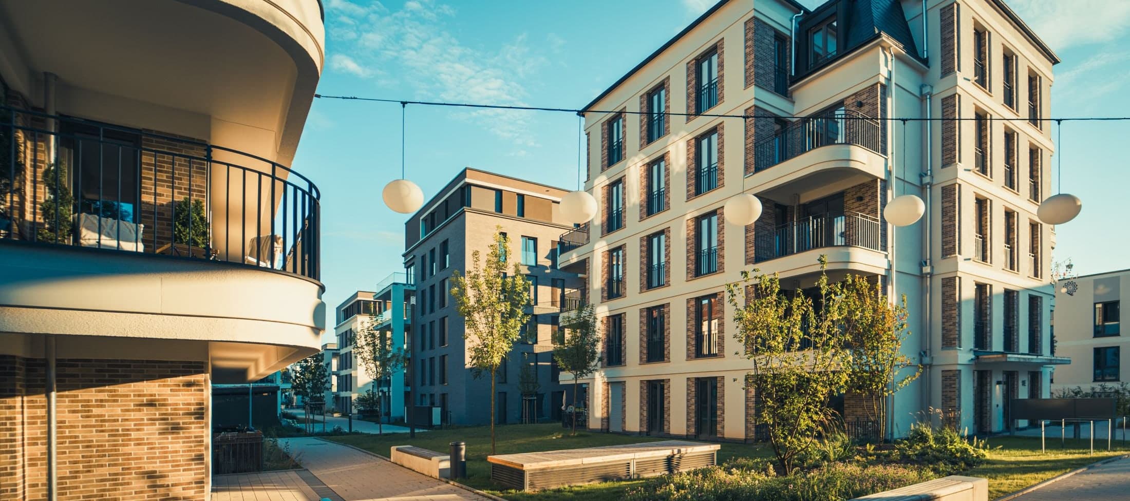 Asuinkerrostalojen piha-alue iltapäivän valossa